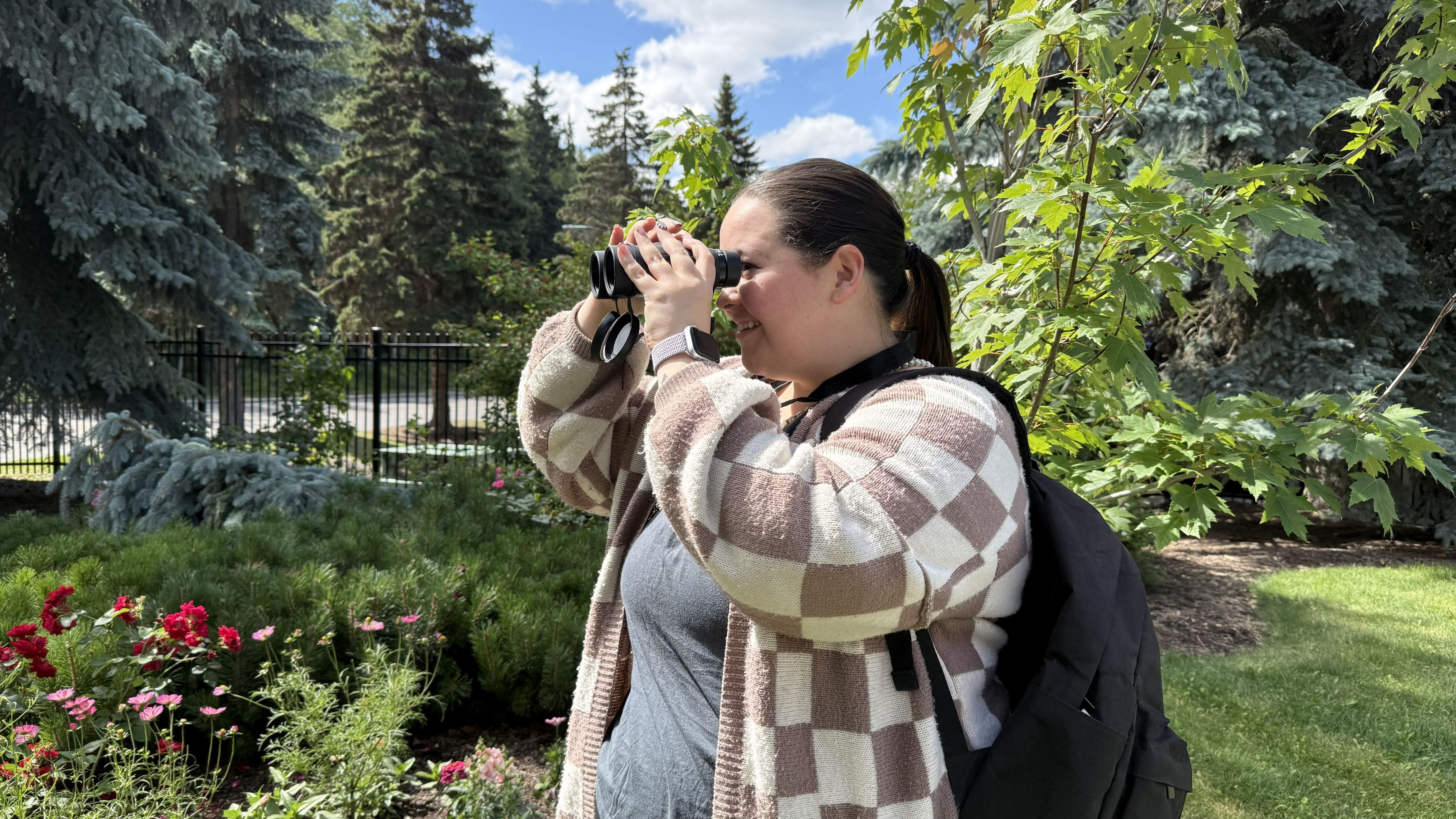 A person holding a set of binoculars up to their eyes